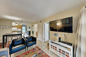 a living room with a large television and a kitchen at Spa on Port Royal Sound II in Hilton Head Island