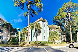 a white building with palm trees in front of a street at Fiddlers Cove III in Hilton Head Island