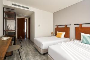 a hotel room with two beds and a desk at Em Oi Boutique Hotel in Nha Trang