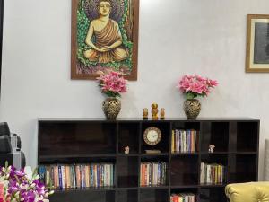 une étagère avec deux vases et une peinture d'un buddha dans l'établissement Krishna Kunj, à Rānchī