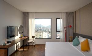 a hotel room with a bed and a desk and a window at Em Oi Boutique Hotel in Nha Trang