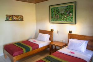 um quarto com duas camas e um quadro na parede em Flamboyan Hotel em Kuta