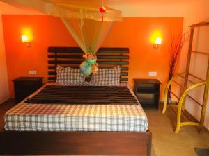 a bedroom with a bed with an orange wall at orchid villa in Ella