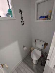 a white bathroom with a toilet and a window at The Cottage on George Street in Jarrahdale