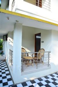 einen Balkon eines Hauses mit zwei Stühlen und einem karierten Boden in der Unterkunft Devi Kripa Residency in Varkala