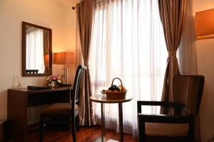 a room with a desk and a table and a window at Raaj Bhaavan Clarks Inn Chennai in Chennai