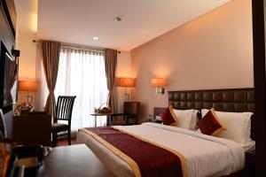 a hotel room with a large bed and a chair at Raaj Bhaavan Clarks Inn Chennai in Chennai