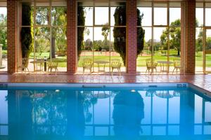einen Pool mit Tischen, Stühlen und Fenstern in der Unterkunft Country Club Tasmania in Launceston
