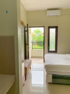 a bedroom with two beds and a balcony at Gumitish Guest House Singaraja in Singaraja