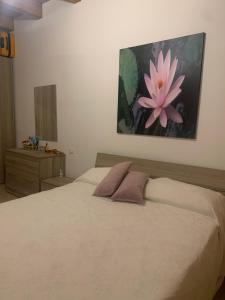 um quarto com uma cama grande com uma flor rosa na parede em Casa Dodò al mare di Soverato em Soverato Marina