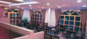 un restaurante con sillas, mesas y ventanas en Al Noor Palace, en Bangalore