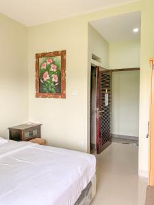 sypialnia z łóżkiem i zdjęciem na ścianie w obiekcie Gumitish Guest House Singaraja w mieście Singaraja