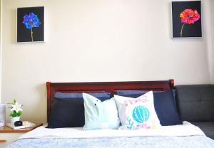 ein Schlafzimmer mit einem Bett mit Kissen und zwei Bildern in der Unterkunft BREATHTAKING TAAL VIEW! TAGAYTAY WIND RESIDENCES MODERN SUITE 23F in Tagaytay