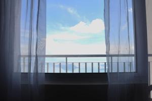 einen Blick auf das Meer von einem Fenster mit Vorhängen in der Unterkunft BREATHTAKING TAAL VIEW! TAGAYTAY WIND RESIDENCES MODERN SUITE 23F in Tagaytay