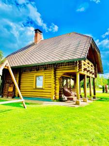 Cabaña de madera con porche en un campo de césped en Brīvdienu māja Odumiņi, en Leimaņi