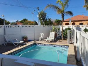 una piscina en un patio trasero con una valla blanca en The White House Lodge en Ciudad del Cabo