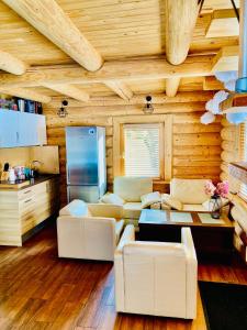 una sala de estar con muebles blancos en una cabaña de madera en Brīvdienu māja Odumiņi, en Leimaņi