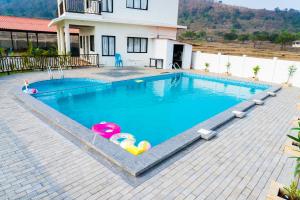 uma piscina com dois insufláveis em frente a uma casa em Eden Garden em Alibaug