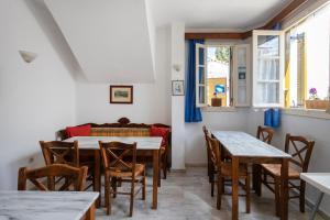 a dining room with tables and chairs and windows at Villa Kalomira in Spetses +31 photos