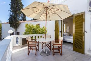 a patio with a table and chairs and an umbrella at Villa Kalomira in Spetses