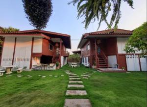 a house with a grass yard with a pathway at Wooden hostel in Chiang Mai