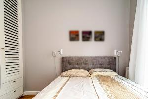 a bed in a bedroom with two paintings on the wall at VIP Apartamenty Białystok in Białystok