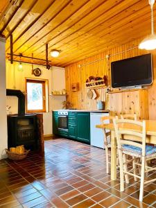 a kitchen with a table and a tv on the wall at Family Peace Chalet Brinovska & Scenic Mt Views in Ortnek