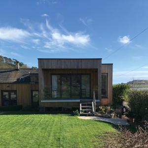 una pequeña casa de madera con césped delante en Uplands Garden, en Morecombelake