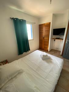 un grand lit blanc dans une chambre avec une fenêtre dans l'établissement PALM SPRING, au Gosier 11 autres photos