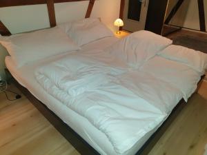uma cama não feita com lençóis e almofadas brancas em Mornag AG Ferien Wohnung em Weesen