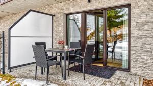 a table and chairs on a patio with windows at Apartament Bujać w Obłokach Karpatia - 5D Apartamenty in Karpacz