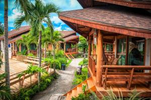 a house with a deck and palm trees at Tique Series Boutique Resort (SHA Extra Plus) in Ban Hat Lek