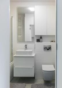 Baño blanco con lavabo y aseo en Tree&Lake Apartament Warszawa en Ząbki