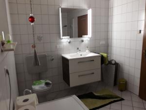 La salle de bains blanche est pourvue d'un lavabo et d'un miroir. dans l'établissement Ferienwohnung Monika Scholtz, à Königheim