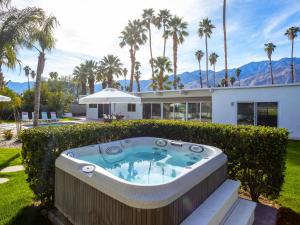 a hot tub in front of a house with palm trees at House of Stardust in Palm Springs