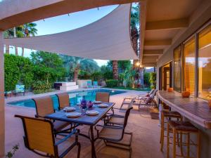 een patio met een tafel en stoelen naast een zwembad bij Reeves Garden House in Palm Springs