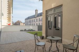 a patio with two chairs and a table and a building at Charmes en Chambertin in Gevrey-Chambertin