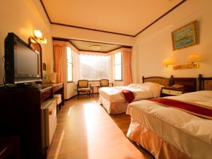 a hotel room with two beds and a flat screen tv at Utopia Holiday Hotel in Heping