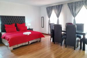 um quarto com uma cama vermelha, uma secretária e cadeiras em Queens Palace em Pretoria mais 4 fotografias