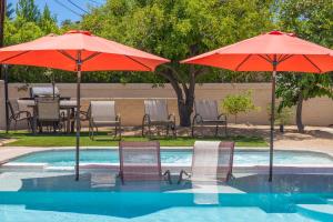 two umbrellas and chairs next to a swimming pool at Boo Boo's Hideaway in Palm Springs