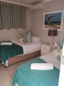 a hotel room with two beds and a lamp at 8A Oyster Crescent in Durban