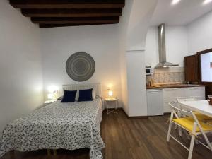 1 Schlafzimmer mit einem Bett mit einem Tisch und einer Küche in der Unterkunft Apartamentos Turísticos Mamelón in Jerez de la Frontera