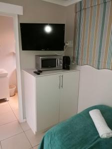 TV en la parte superior de un armario blanco con microondas en 8A Oyster Crescent en Durban