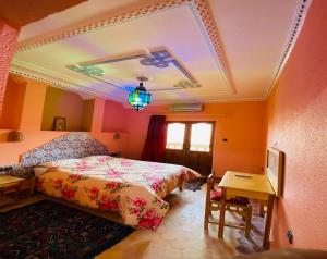 una camera con letto, tavolo e soffitto di La Perle Du Drâa a Zagora