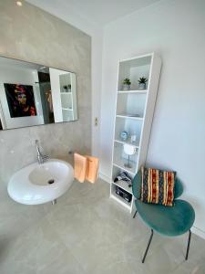 a bathroom with a sink and a chair at Villa am Steinhuder Meer App Suite-La Fleur-mit Pantry Küche, Luftreinigungssystem, Garten, WLAN in Steinhude