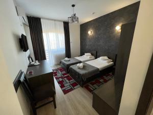 um quarto de hotel com duas camas e uma secretária em Motel Infinit em Târgu Jiu