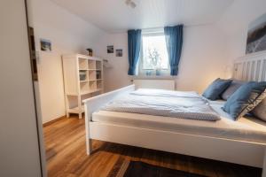 a bedroom with a bed with blue curtains and a window at Nordseehof Brömmer in Wremen