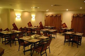 Hotel Gnanam في ثانجافور: غرفة طعام مع طاولات وكراسي وستائر