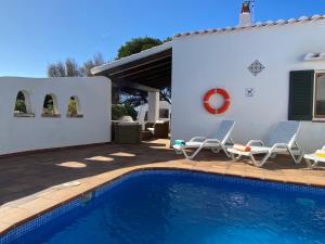 a villa with a swimming pool in front of a house at Villa con piscina privada y gran jardín in Cala en Bosc