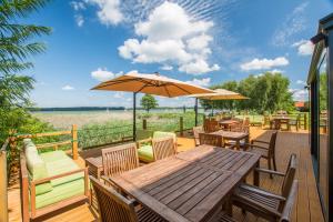 a wooden table and chairs with an umbrella on a deck at Stanica Żeglarska Otago in Pisz